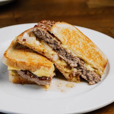 Patty melt sandwich on a white plate.