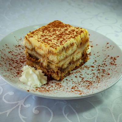 Tiramisu dusted with cocoa powder and served with whipped cream.
