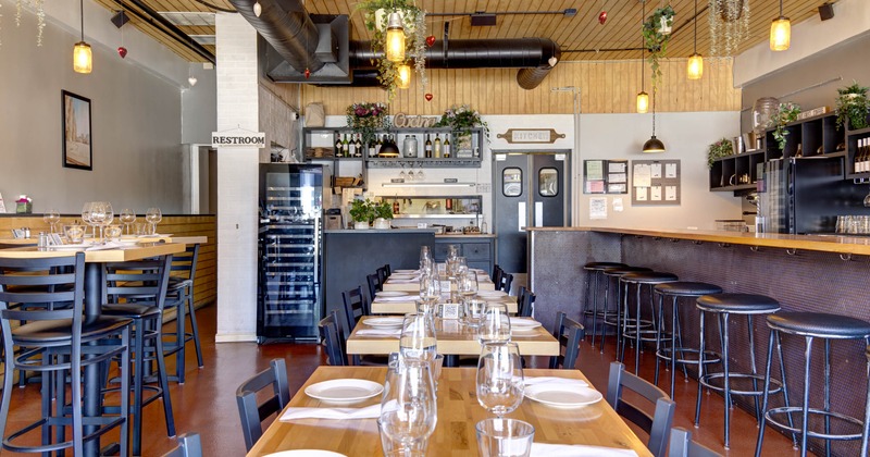 Interior with wooden tables, black chairs, and a bar with stools