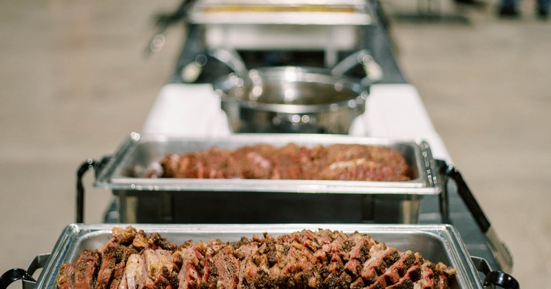 Catering buffet line with sliced smoked brisket in stainless steel pans