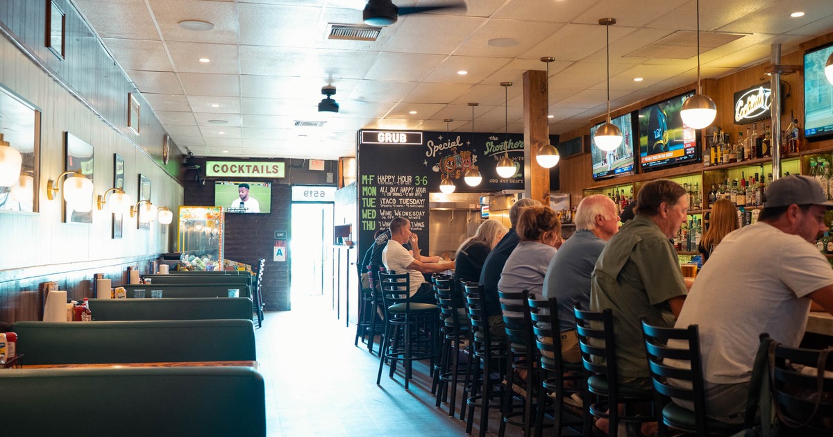 Interior, people sitting at the bar counter with dining booths lining a wall