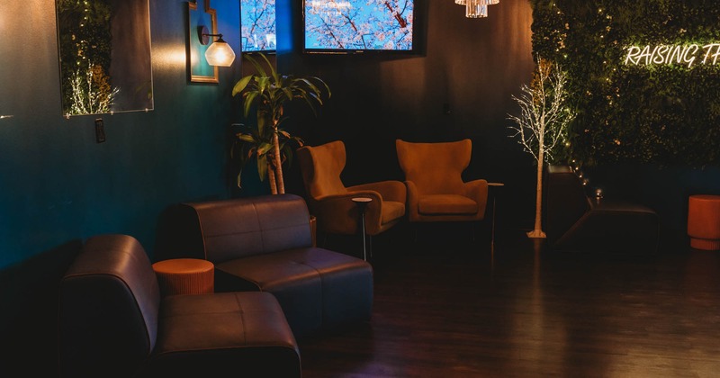 Interior, lounge area, comfortable chairs with coffee tables, green wall with neon signage