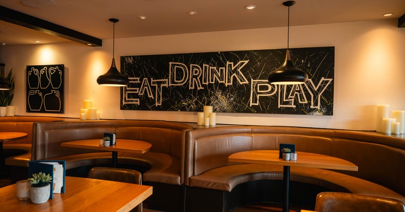 Interior, dining area, U shaped seating booths with wooden top tables, paintings as a decoration