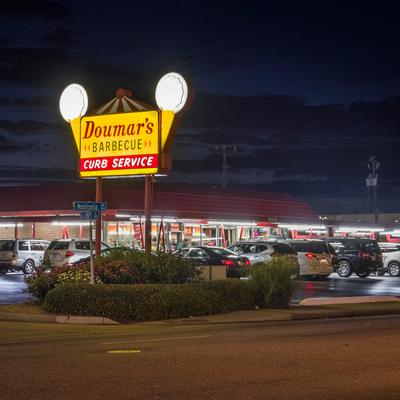 exterior, nighttime picture of iconic sign and cars on the curb.