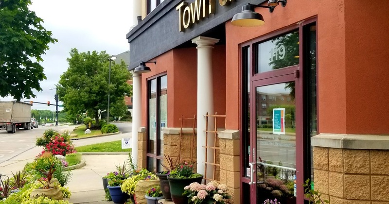 An outside photo of the building with the front door and several pots of flowers