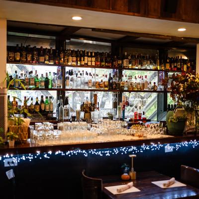 Bar area featuring shelving densely packed with numerous liquor bottles.