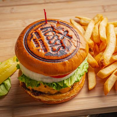 Cheeseburger with crispy fries on a wooden cutting board.