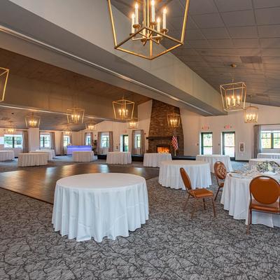 A spacious room for events with elegantly arranged tables covered with white tablecloths.