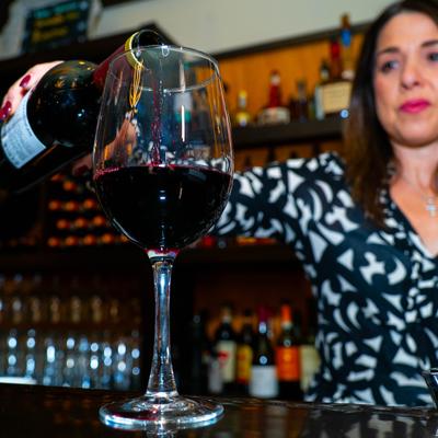 Staff member pouring red wine into a glass.