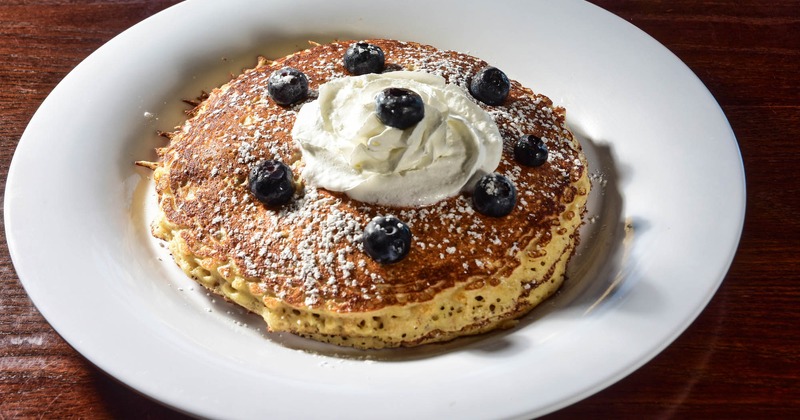 Oatmeal pancakes topped with whipped cream, blueberries, and powdered sugar