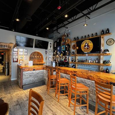 The bar are with a wooden counter, stools, and beer taps.