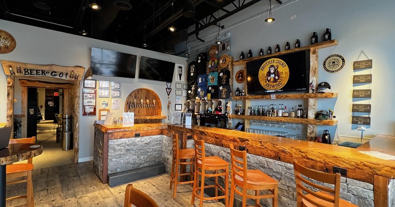 The bar are with a wooden counter, stools, and beer taps