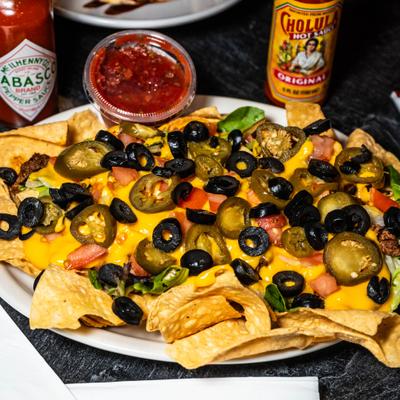 Supreme Nachos with cheese sauce, taco meat, tomatoes, black olives and jalapeños.