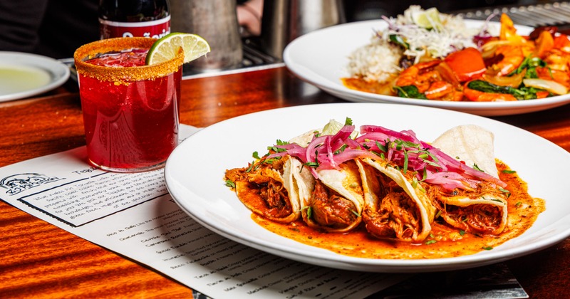 Various dishes served on the table with menus and a cocktail