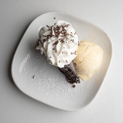 Chocolate cake with whipped cream, chocolate sprinkles, and a scoop of ice cream.
