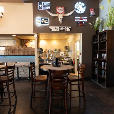 Interior featuring high-top wooden tables, bar stools and various decorative signs.