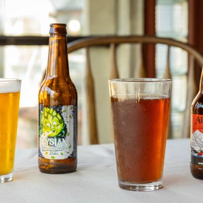 Beer glasses and bottles arranged on white tablecloth.