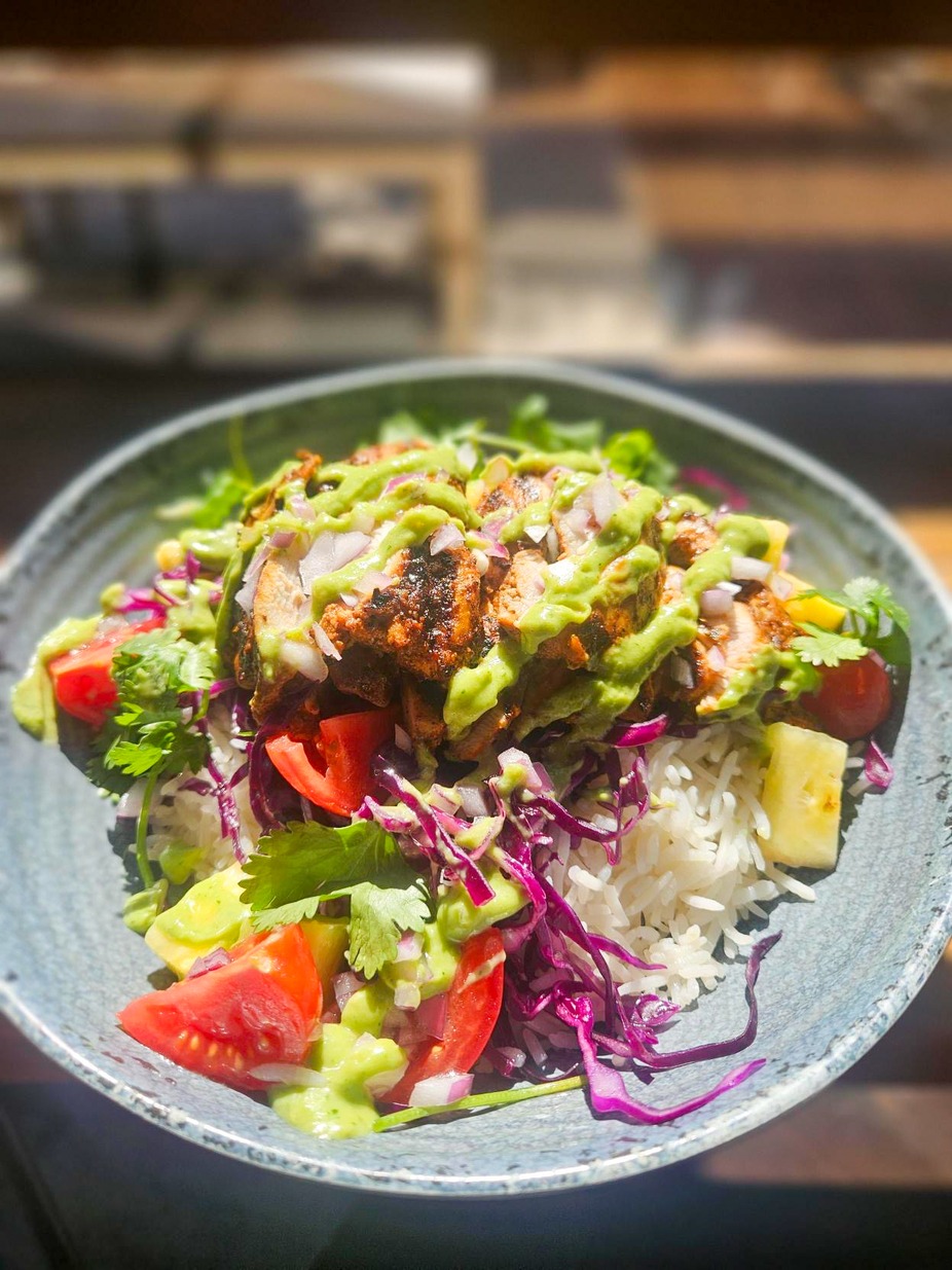 Al Pastor Chicken Bowl - Grilled pastor-marinated chicken thigh over white rice topped with purple cabbage, marinated tomatoes, pineapple, red onion, cilantro and avocado jalapeño dressing
