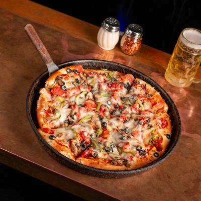 Deep Dish pizza and a beer on a table.