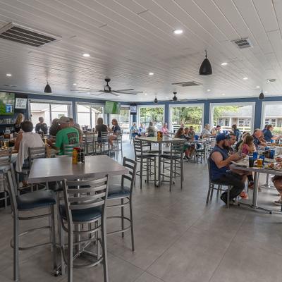 A brightly lit modern restaurant with patrons seated at metal tables.