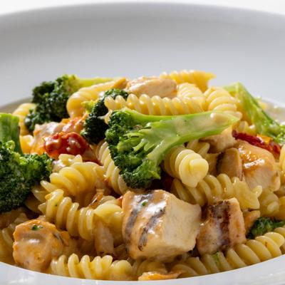 Fusilli pasta with chicken, broccoli, and sun - dried tomatoes in a light cream sauce.