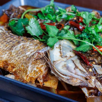 Spicy whole fish with vegetables, dried chilies, and cilantro.