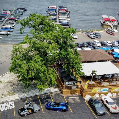 A high angle shot of the restaurant, lake dock, cars and trees.