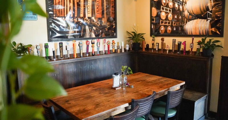Rustic dining nook with wooden table, beer tap handles, and brewery wall art