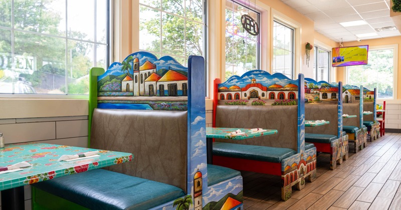 Interior, dining area, booths with tables, painted benches depicting traditional Mexican buildings