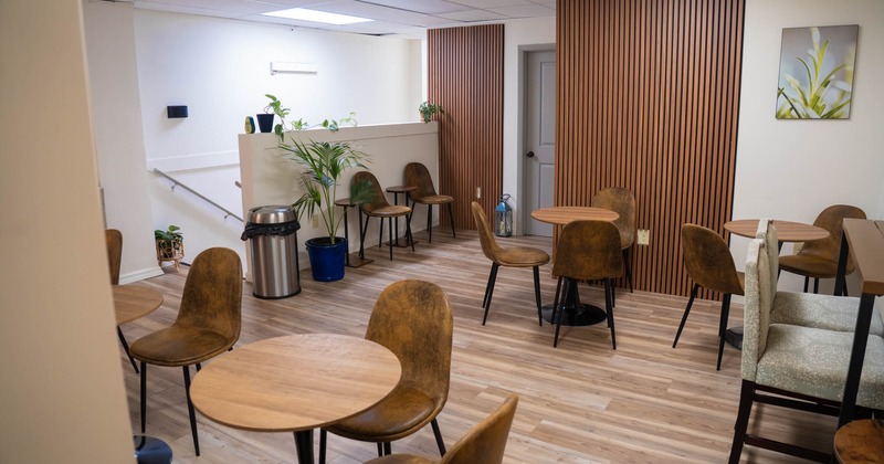 Modern lounge area with wooden tables, brown chairs, and indoor plants