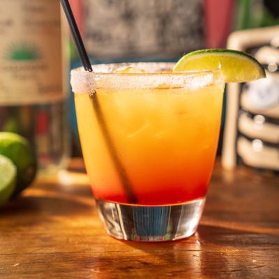 An orange cocktails with a lime slice.