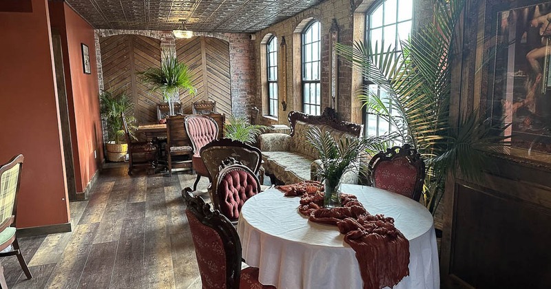 A vintage-style interior - a table set for decor, ornate chairs, tall windows, a decorative ceiling