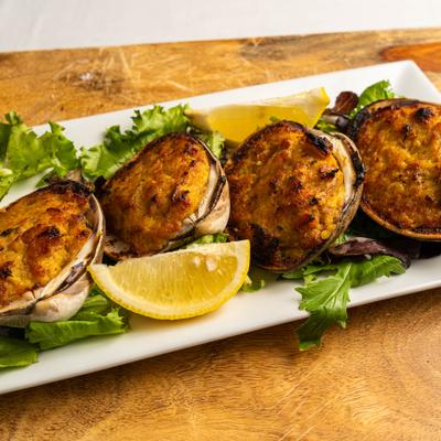 Baked stuffed clams on a bed of greens, served with lemon wedges.