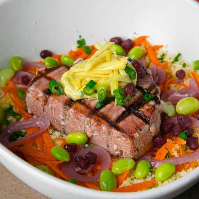 Grilled ahi tuna bowl with herb and butter couscous, edamame, pickled ginger, and carrot.