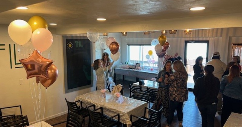 Indoor space decorated for a celebration with people standing