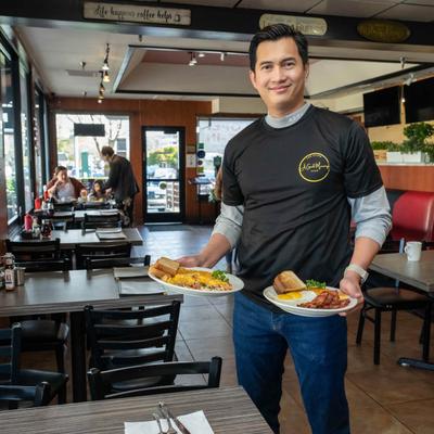 Employee holding meal plates in dining area