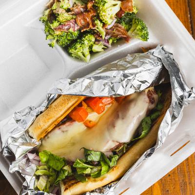 Italian Stallion Sub wrapped in foil and served with a side salad.
