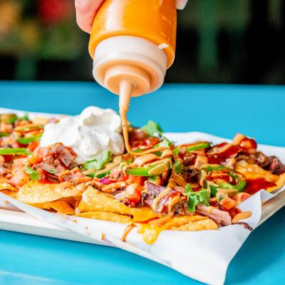 Brisket nachos drizzled with a creamy orange sauce from a squeeze bottle.