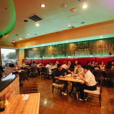 Crowded restaurant dining space with warm lighting and seating.
