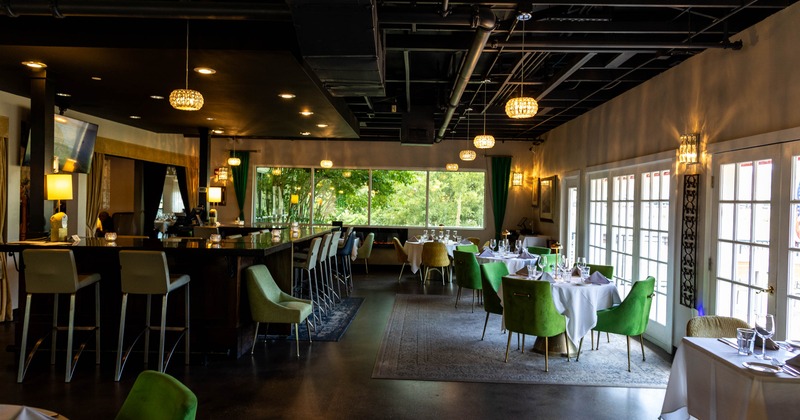 Interior, dining and bar area, round tables for four, bar with stools on the left