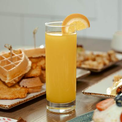 Glass of Orange juice surrounded by food plates.