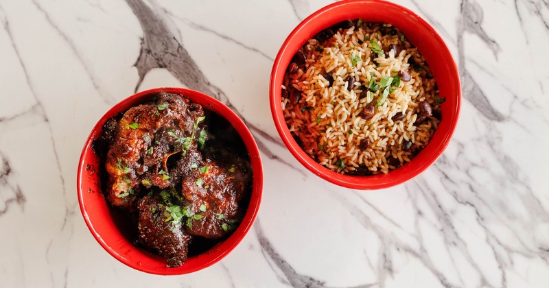 A bowl of slow braised oxtails paired with a bowl of rice and peas