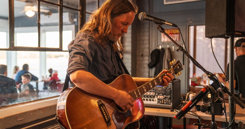 Person performing with an acoustic guitar, indoors