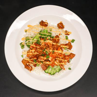 Chicken and vegetables over rice drizzled with creamy yellow sauce.