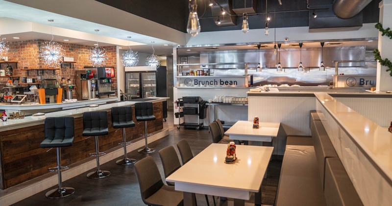 Interior of a modern café with a mix of high and low seating, exposed brick, and kitchen area