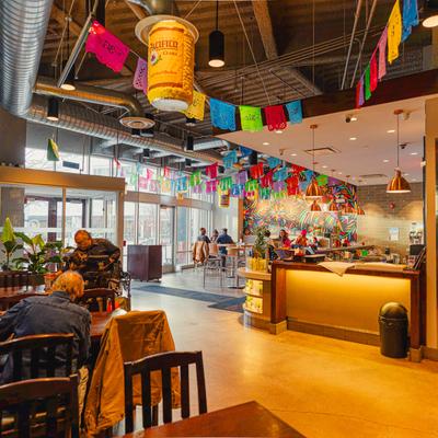 Colorful Mexican restaurant interior with papel picado banners, bar area, and seating.