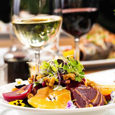 Decorated salad with fruit and vegetables, glass of white wine on the side
