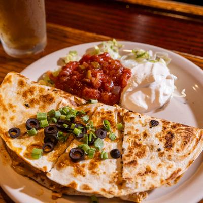 Chicken Quesadilla topped with chives and black olives, served with with salsa and sour cream.