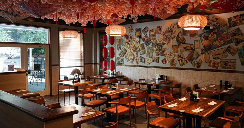 A cozy restaurant with wooden tables and chairs, paper lanterns
