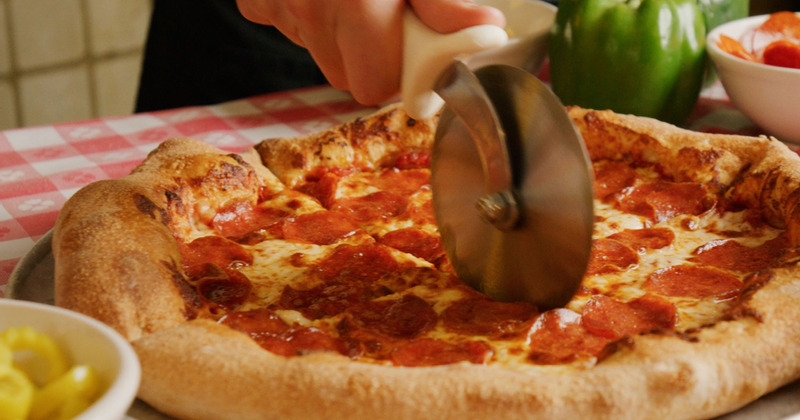 A person cutting a pizza